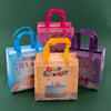 A set of colorful reusable happy birthday gift bags in pink, orange, and purple are displayed on a green surface.