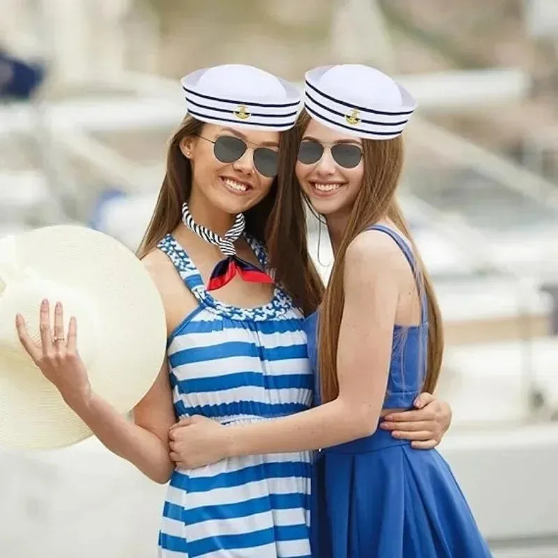 Two women smiling wearing a classic captain's hat and scarf set, posing outdoors.