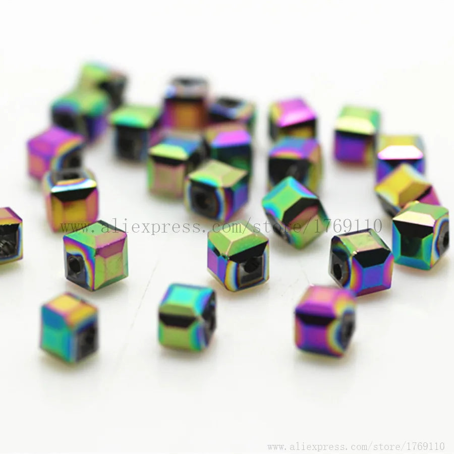 A collection of square cut glass crystal beads in various iridescent colors scattered on a white surface.