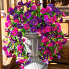 A vibrant arrangement of artificial hanging silk morning glory flowers in shades of purple and magenta displayed in a gray ur