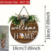 A round wooden welcome sign with the text welcome to our home surrounded by green foliage and a bow.