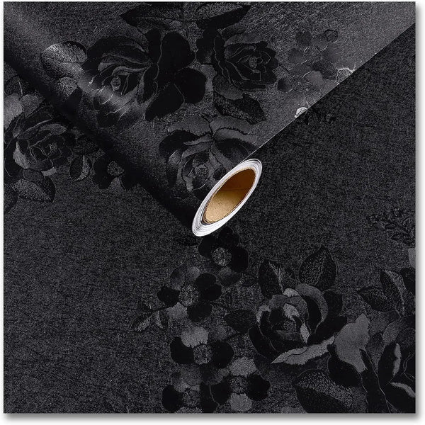 A sheet of vintage black floral self-adhesive contact paper is shown diagonally, revealing a rolled edge.