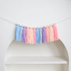 Handmade boho rainbow tassel garland with wooden beads featuring shades of blue, purple, and pink.