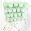 A set of twenty light green spherical ball cake toppers on thin green stems.