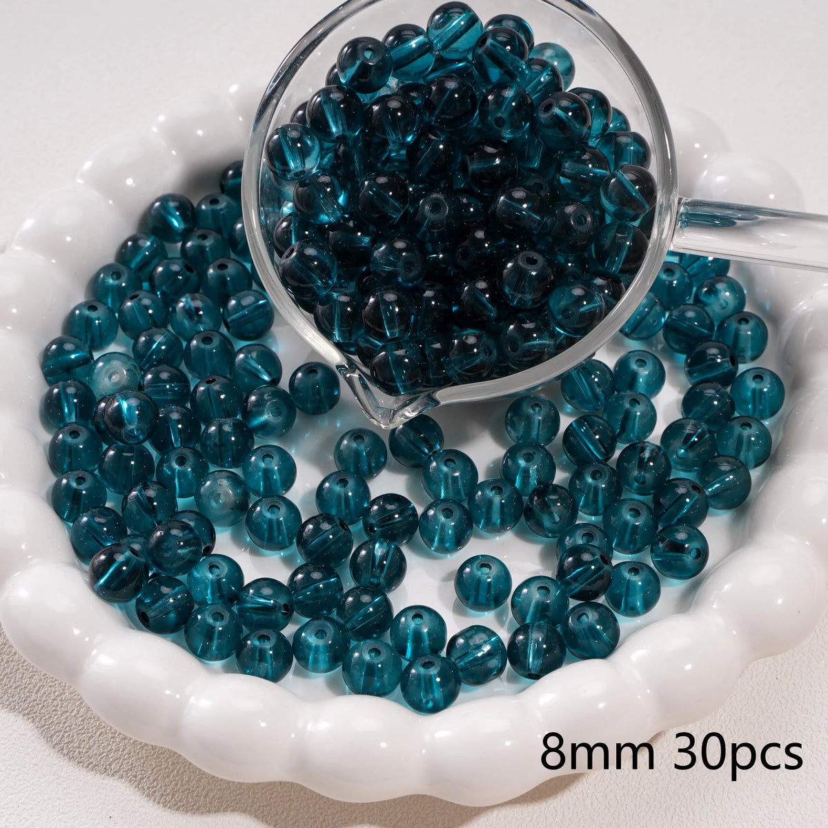 A clear glass jar filled with dark blue round spacer beads for jewelry making