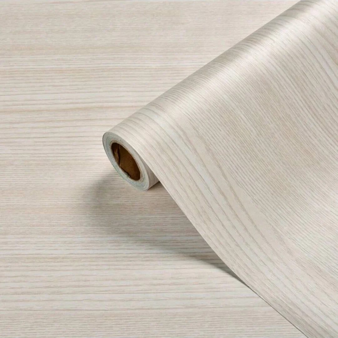 Roll of self-adhesive PVC wallpaper film with a light wood grain texture on a surface.