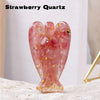 A pink strawberry quartz figurine shaped like a guardian angel, resting on a light surface.