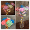 A collection of glowing gold foil roses in various shades of pink, blue, and white arranged in a glass vase.