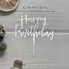 Silver acrylic birthday sign with the words Happy Birthday on a wooden surface
