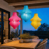 A set of handmade vintage flower bottle lanterns hanging in front of a modern house at twilight.