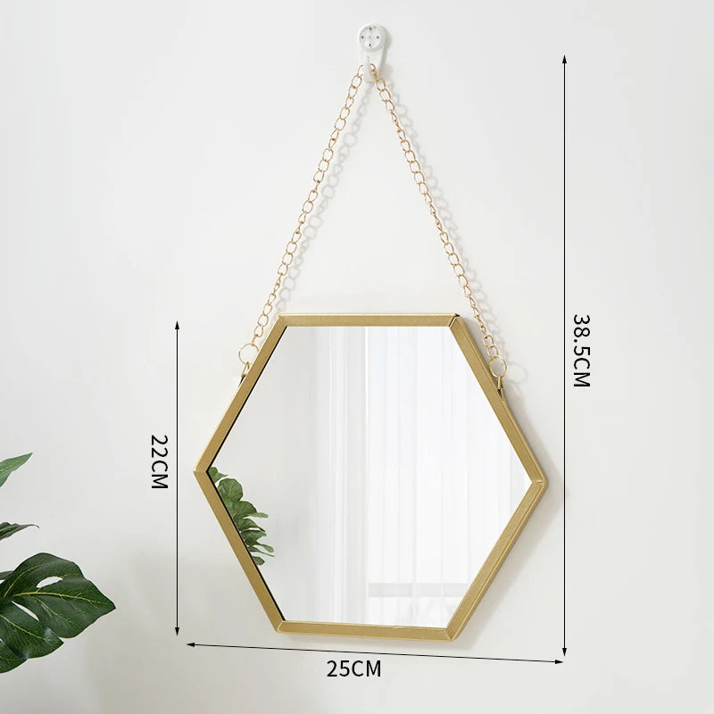 A gold-framed hexagon wall mirror hanging by a chain, shown against a white background.