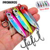 A hand holds a set of metal jig fishing lures with hooks and a storage box.