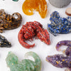 A collection of natural crystal dragon figurines in various colors including orange, red, blue, and purple.