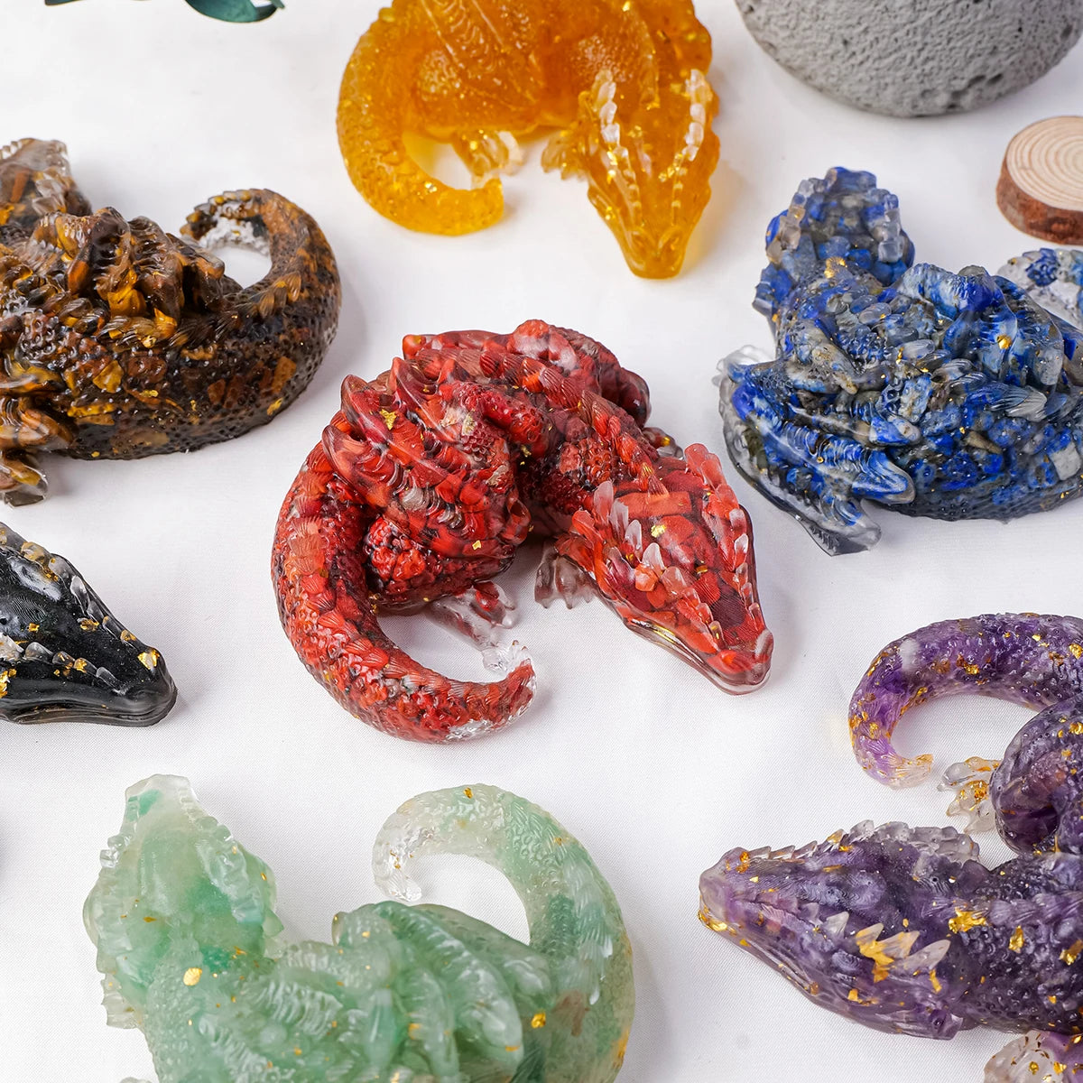 A collection of natural crystal dragon figurines in various colors including orange, red, blue, and purple.