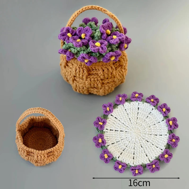 A hand-crocheted basket filled with purple rose flowers, next to a circular coaster made of white yarn and purple flowers.