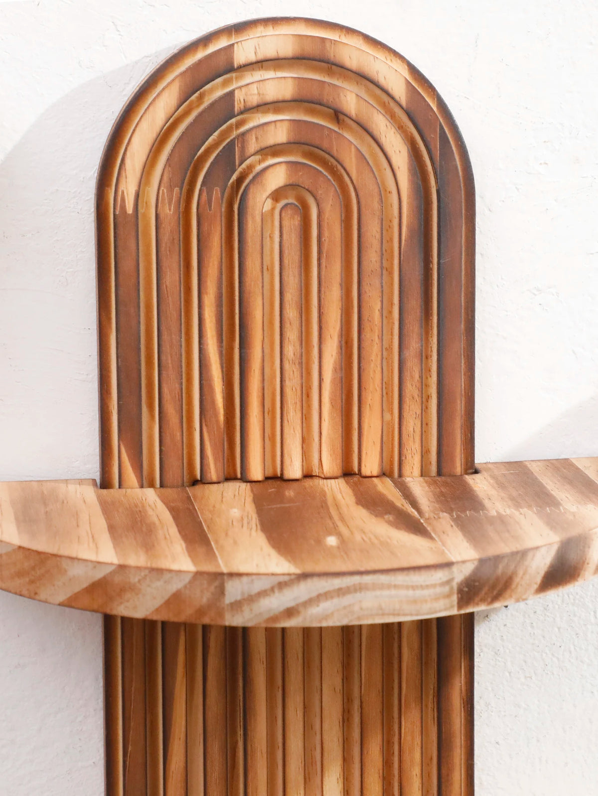 Two wooden wall shelves with arched designs mounted on a white wall.