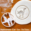 White silicone cookie cutters and fondant stamps shaped like cats on a wooden surface.