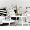 A white table displays a pink resin balloon dog sculpture, greenery, and decorative items in a bright interior setting.
