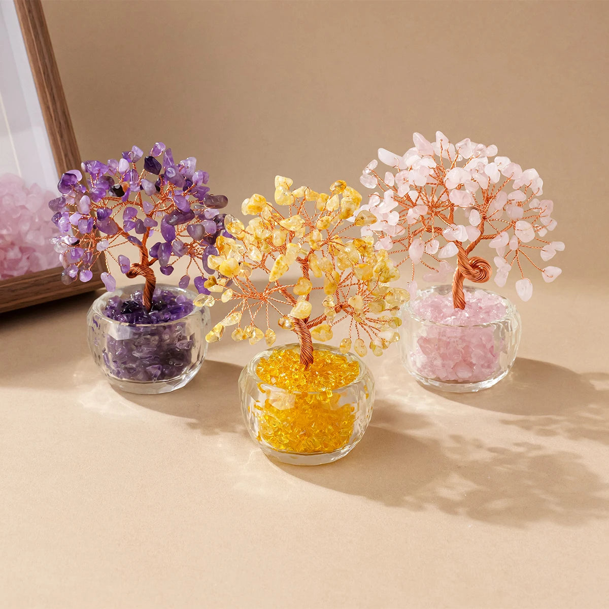 Three crystal money tree ornaments in purple, yellow, and pink hues displayed on a neutral background.