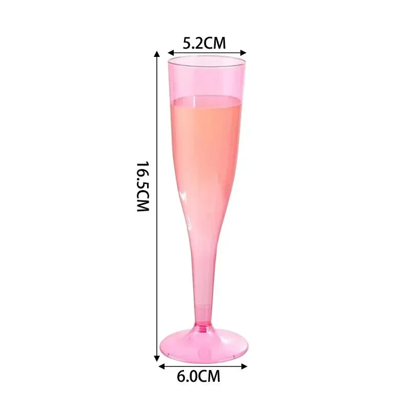 A pink glitter disposable champagne flute with a stem and foot, shown in a vertical dimension view.