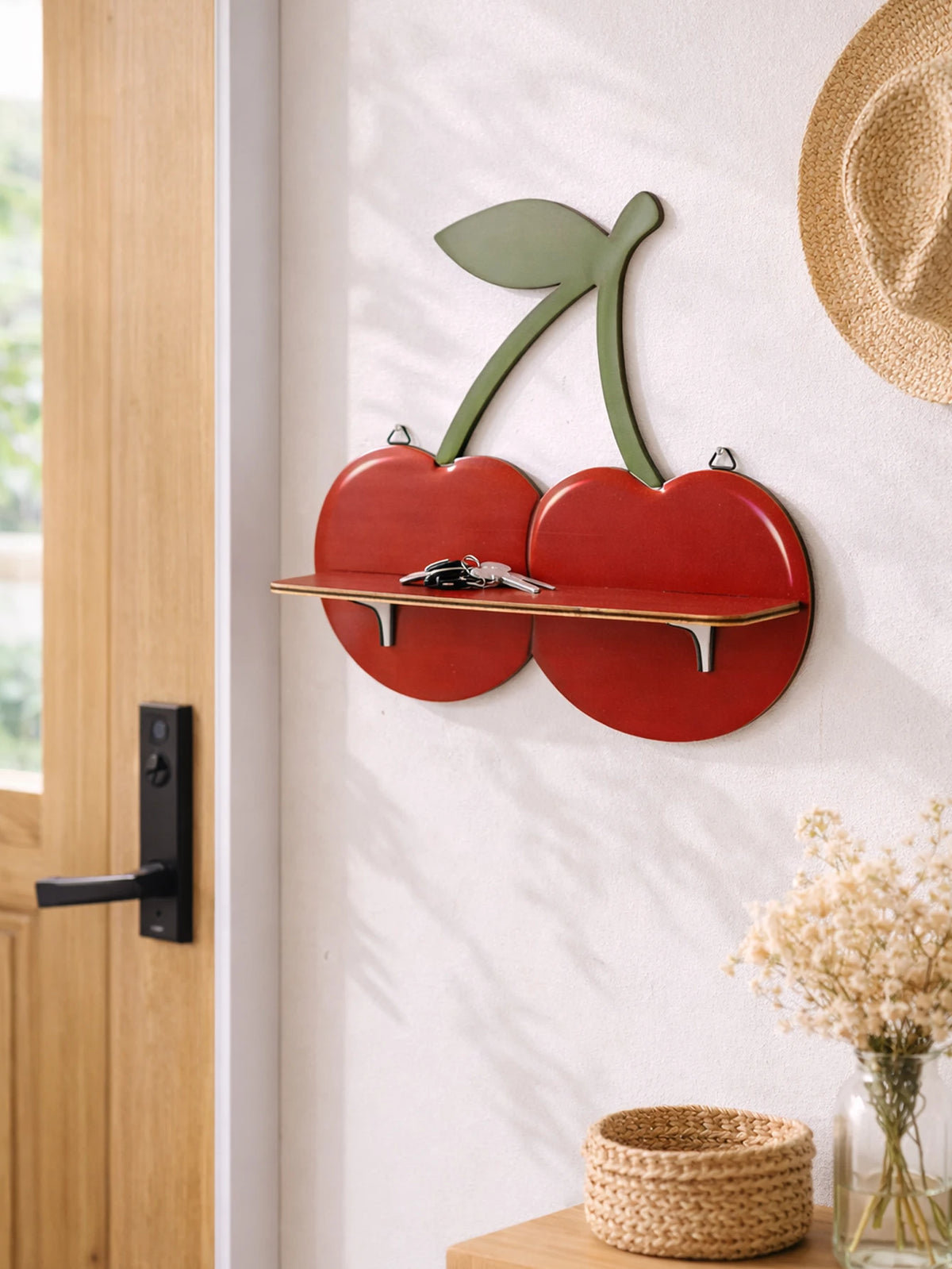 A wooden cherry-shaped wall shelf with a green leaf cutout mounted on a white wall.