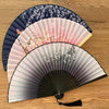 A vintage silk bamboo folding hand fan with a delicate floral pattern in shades of pink and gray.