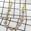 Gold and pink rhinestone bag chain extender with lobster clasps displayed on a white checkered cloth.