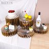 Supports en acrylique pour nourriture présentant un gâteau à la fraise et des fruits jaunes sur une table en bois.
