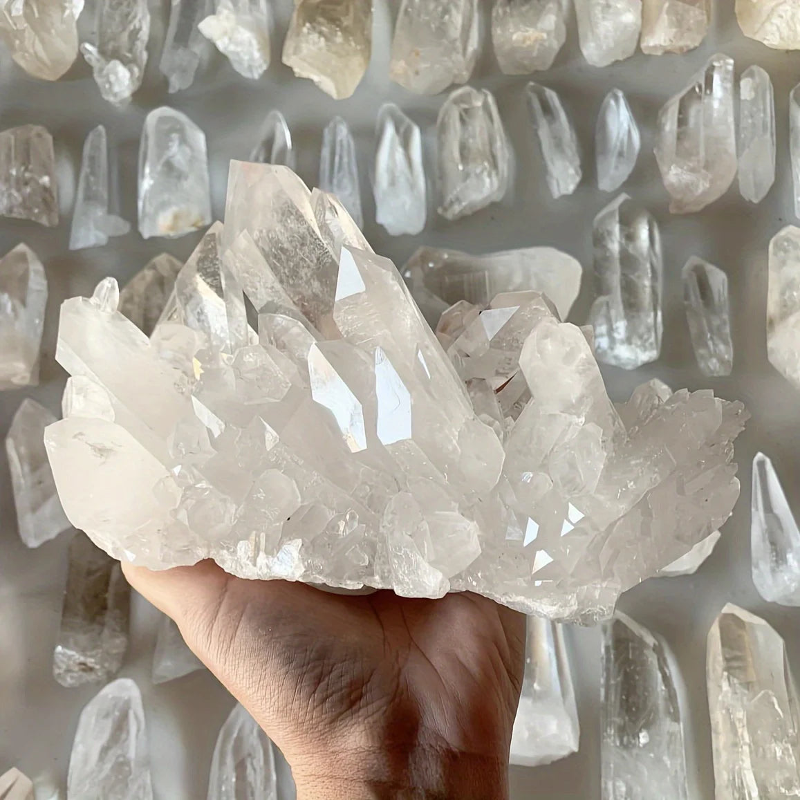 A hand holds a cluster of clear quartz crystals for home decor.