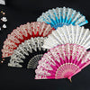 A collection of five elegant folding fans in various colors including red pink white and blue with intricate traditional Chin