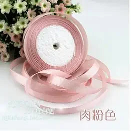 Pink silk satin ribbon rolled into a circular form with a white center.