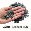 A hand holds a pile of 20 smooth, dark gray river rocks for use in aquariums or art projects.