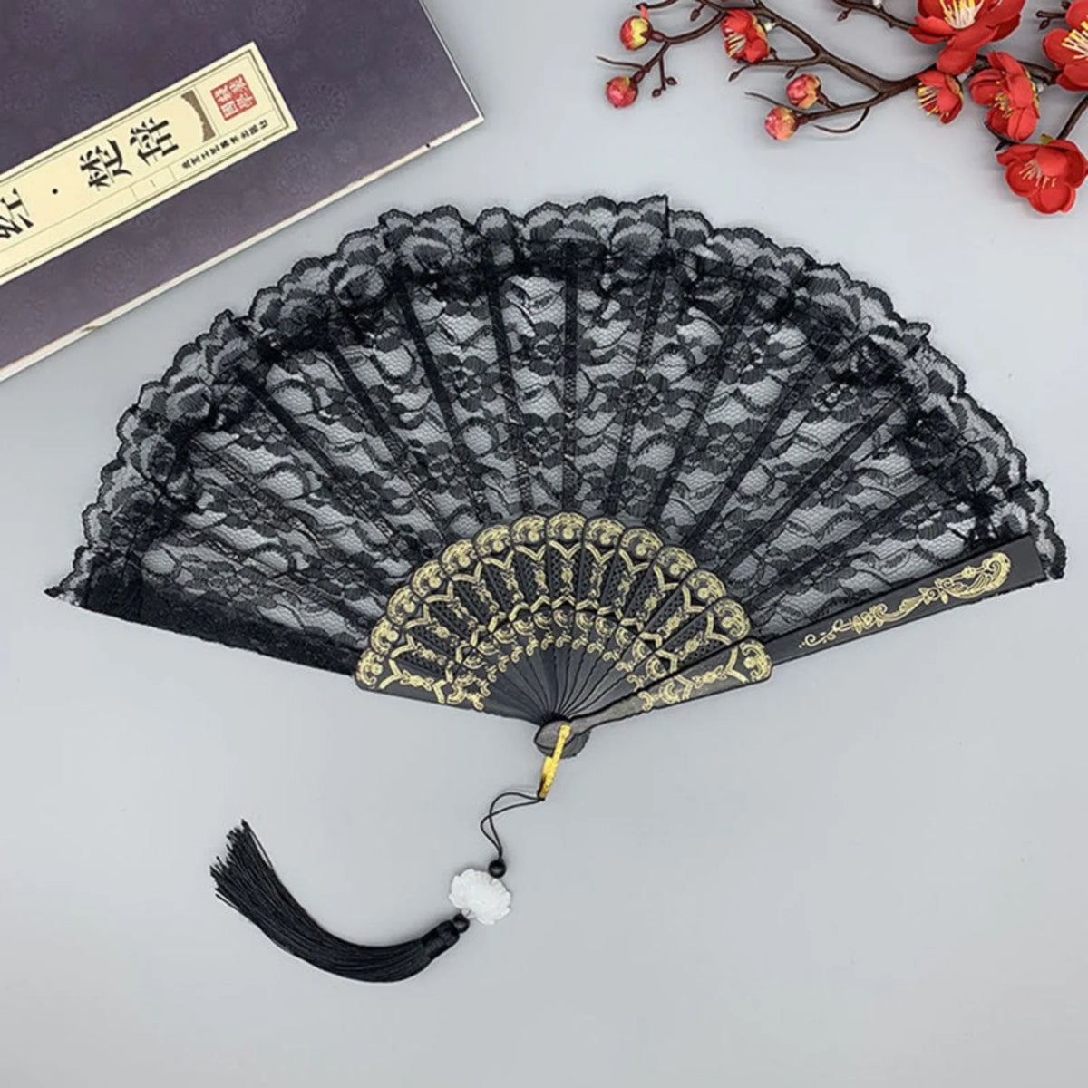 Abanico de mano plegable de encaje vintage negro con detalles dorados y un fleco
