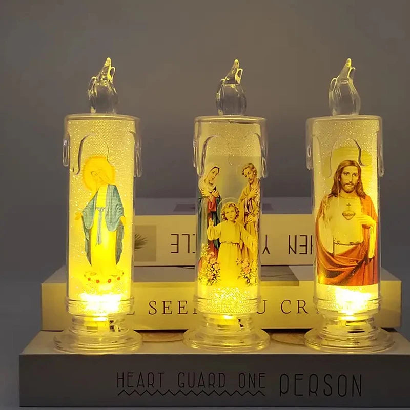 Three clear glass votive candles with yellow and brown religious figures are displayed on a wooden surface.