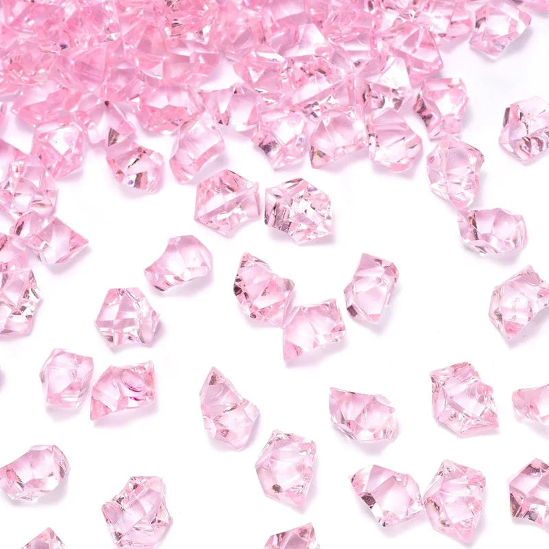 Pink decorative crushed diamond acrylic pebbles scattered on a white background