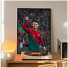 A framed poster of Cristiano Ronaldo in a red and green kit is displayed next to a modern lamp on a wooden table.