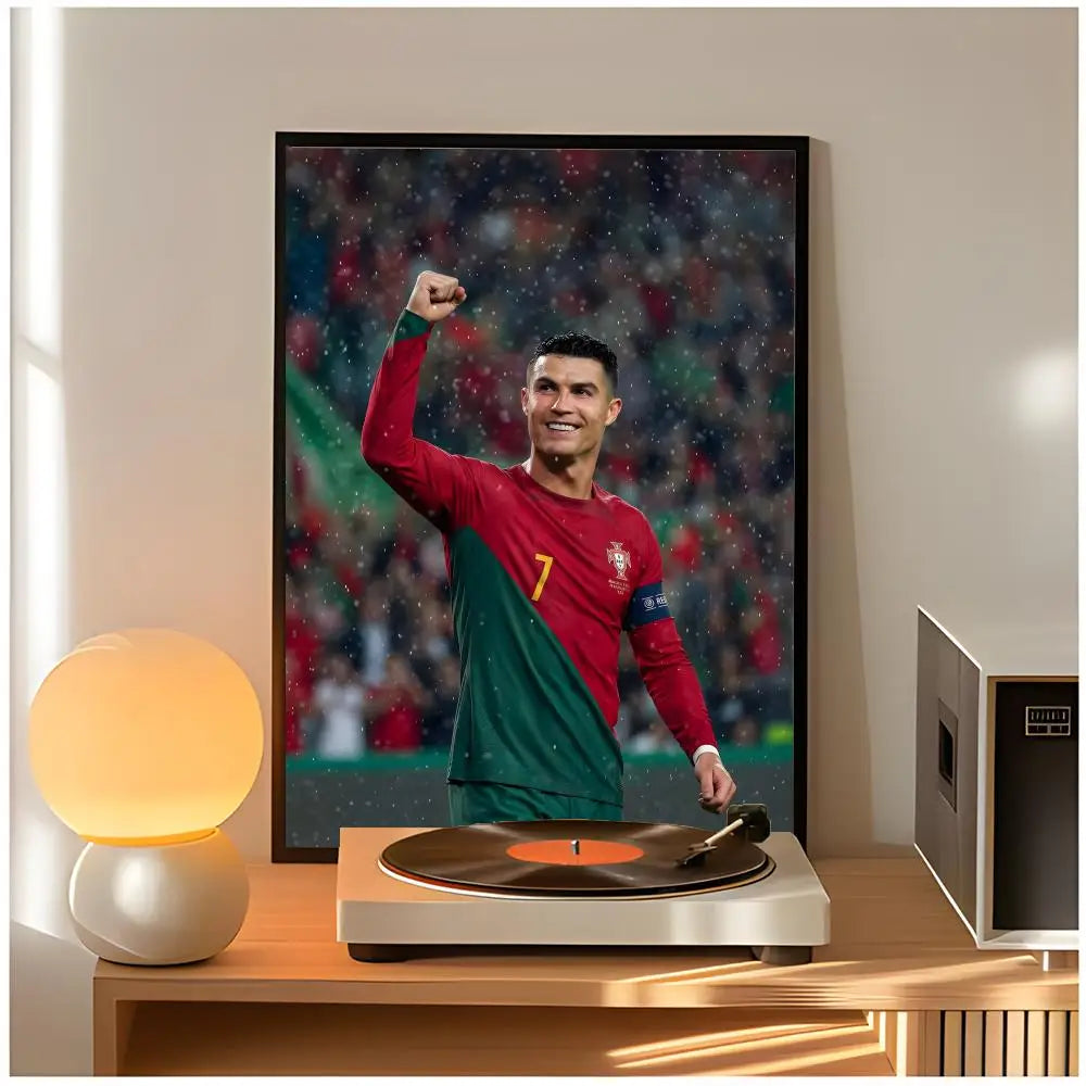 A framed poster of Cristiano Ronaldo in a red and green kit is displayed next to a modern lamp on a wooden table.