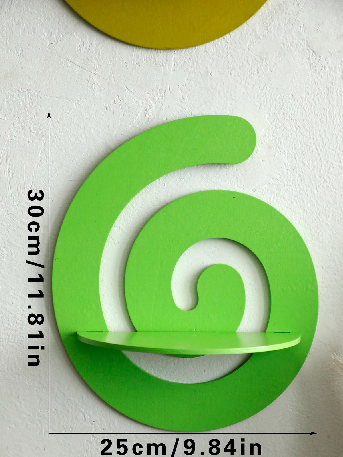 A bright lime green, cherry-shaped wooden wall shelf mounted on a white wall.