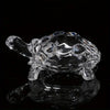 A clear crystal turtle desk ornament reflecting on a dark surface.