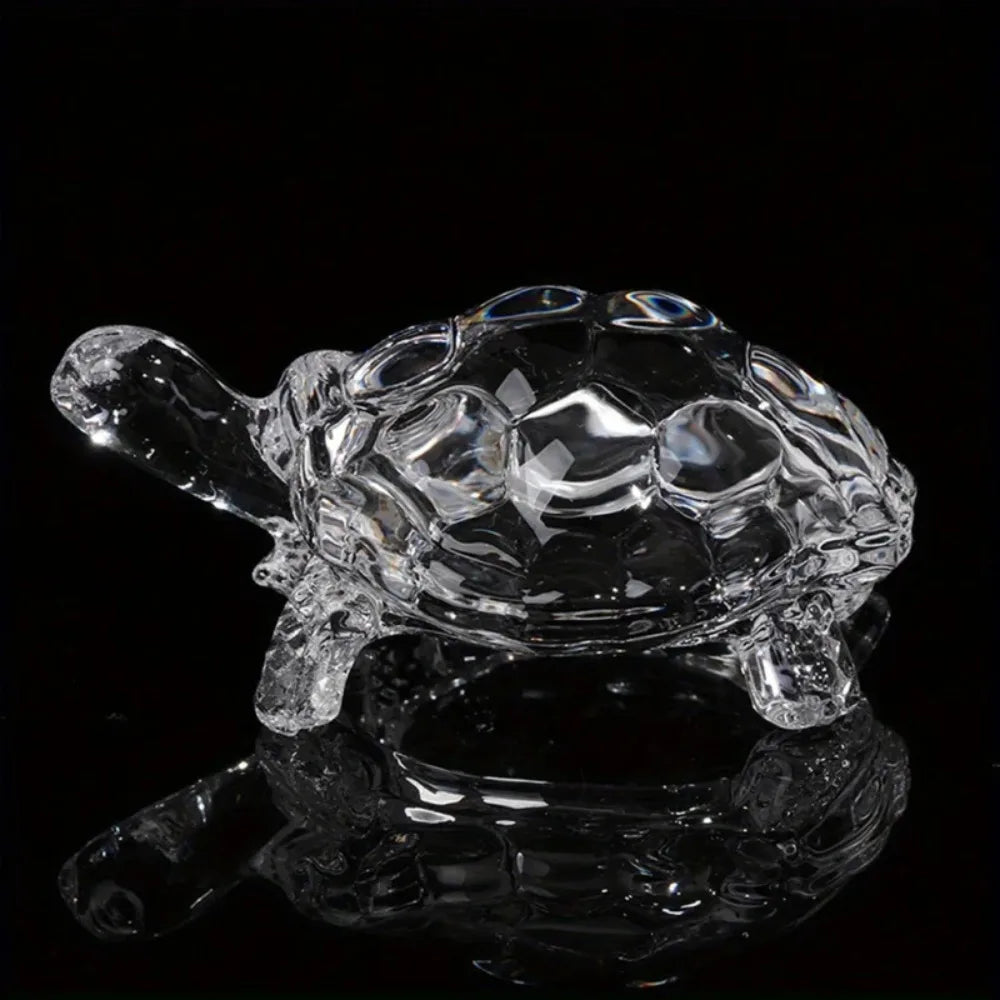 A clear crystal turtle desk ornament reflecting on a dark surface.