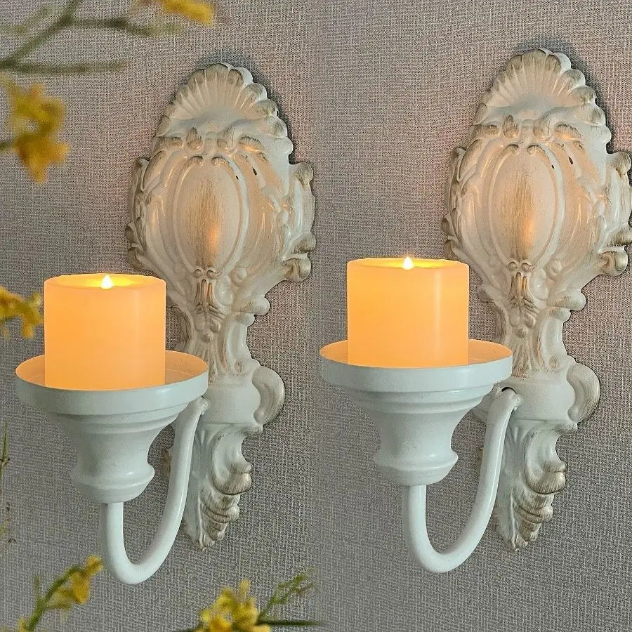 A set of two vintage wrought iron wall-mounted candle holders with white wax candles.