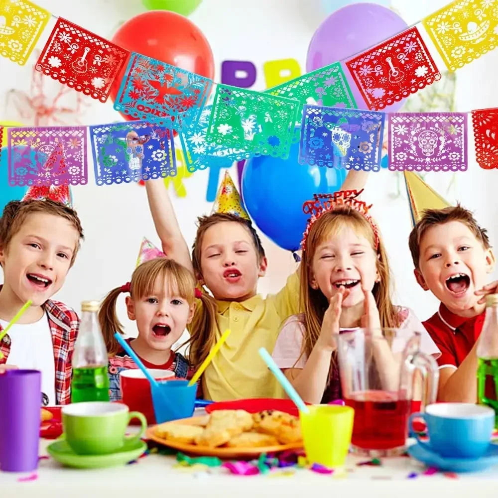 A group of happy children celebrating with a colorful papel picado bunting banner and balloons.