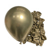 A large, shiny metallic silver latex balloon next to a pile of crumpled gold foil balloons for party decor.