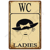 Vintage tin sign with the letters WC and a drawing of a woman labeled LADIES