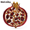 A gold-toned crystal pomegranate brooch pin featuring a deep red, textured design.