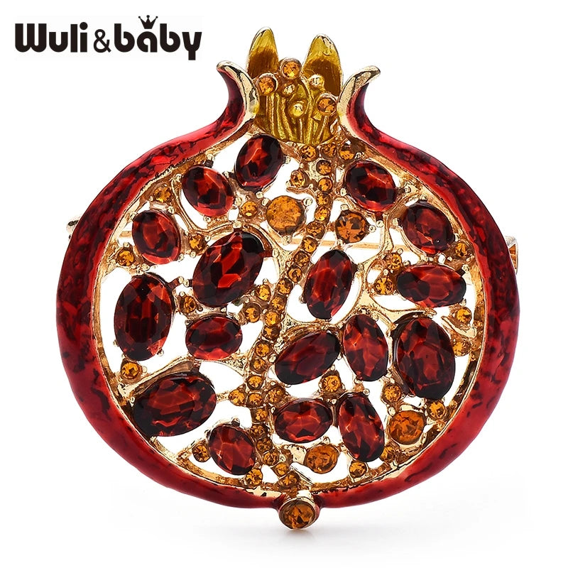 A gold-toned crystal pomegranate brooch pin featuring a deep red, textured design.
