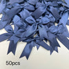 A pile of 50 dark blue satin ribbon bows for gift wrapping and decor.