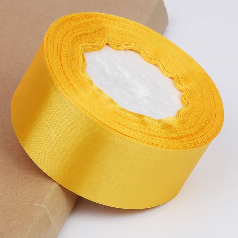 Roll of bright yellow satin ribbon with a white center for crafts and gift wrapping
