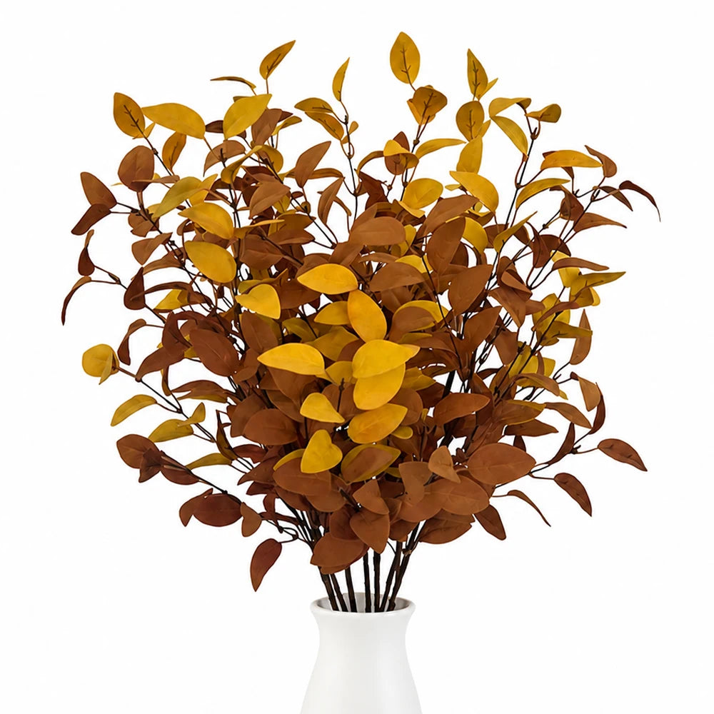 A bouquet of artificial fall eucalyptus stems featuring dried brown and yellow leaves in a white vase.