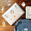 A laptop is decorated with various funny goose cartoon vinyl decals and a blue fabric item.
